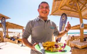 Staff member serving fresh lunch with fries at the KiteHouse Soma Bay beach